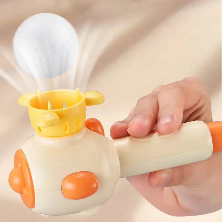 White ball hovering above a yellow basket on a handheld blowing toy.