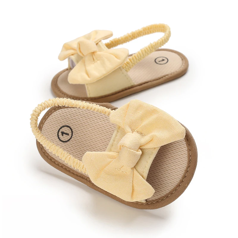 Yellow baby sandals with fabric bows, tan footbeds, and elastic heel straps