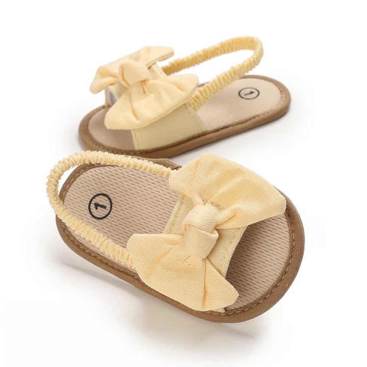 Yellow baby sandals with fabric bows, tan footbeds, and elastic heel straps