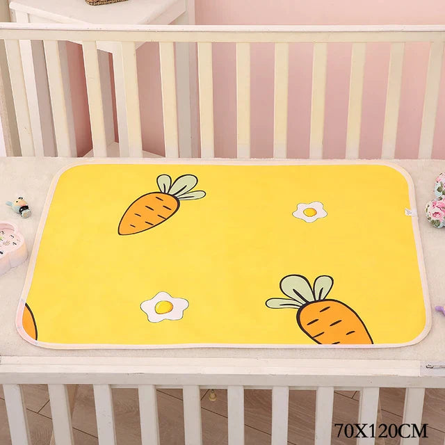 Yellow carrot-print changing mat inside a white crib, labeled 70 x 120 cm.