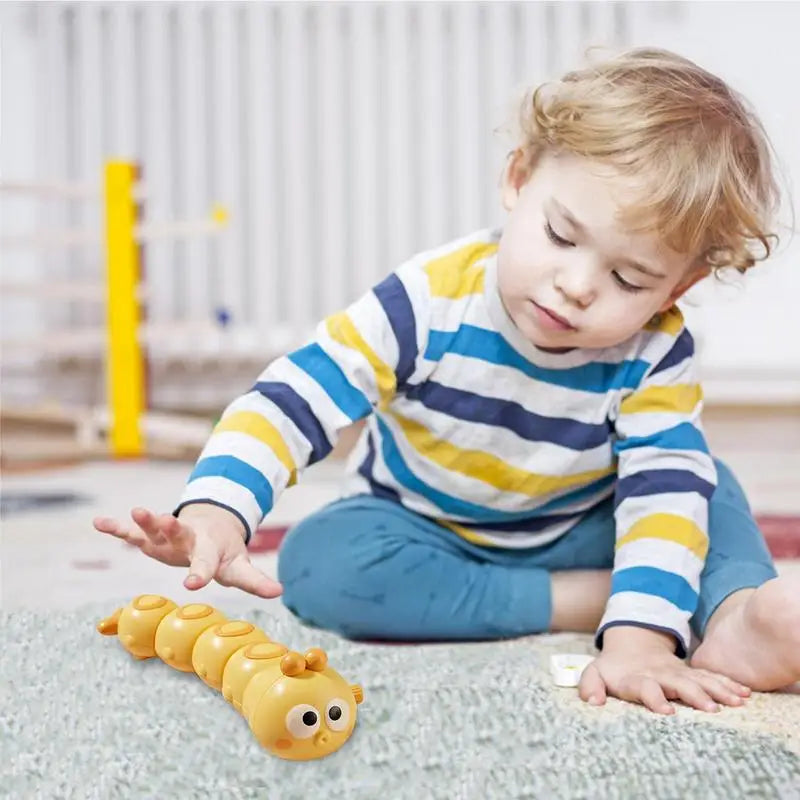 Child reaching toward a yellow wind-up caterpillar toy on a rug