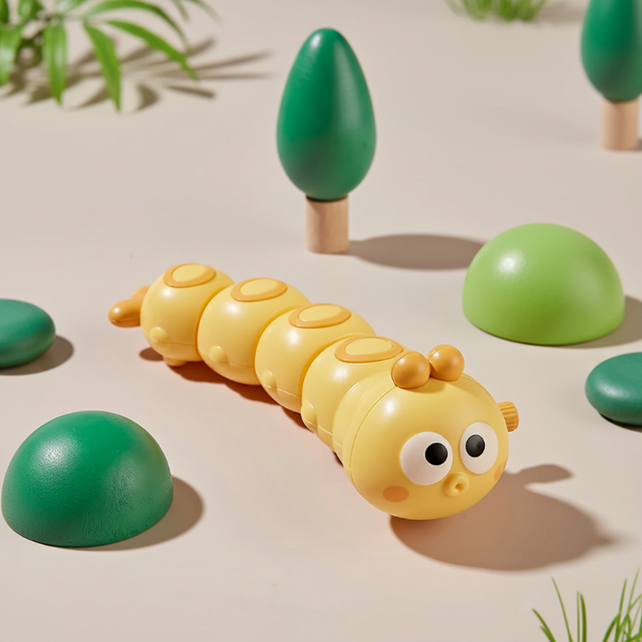 Yellow wind-up caterpillar toy in a display with miniature green trees