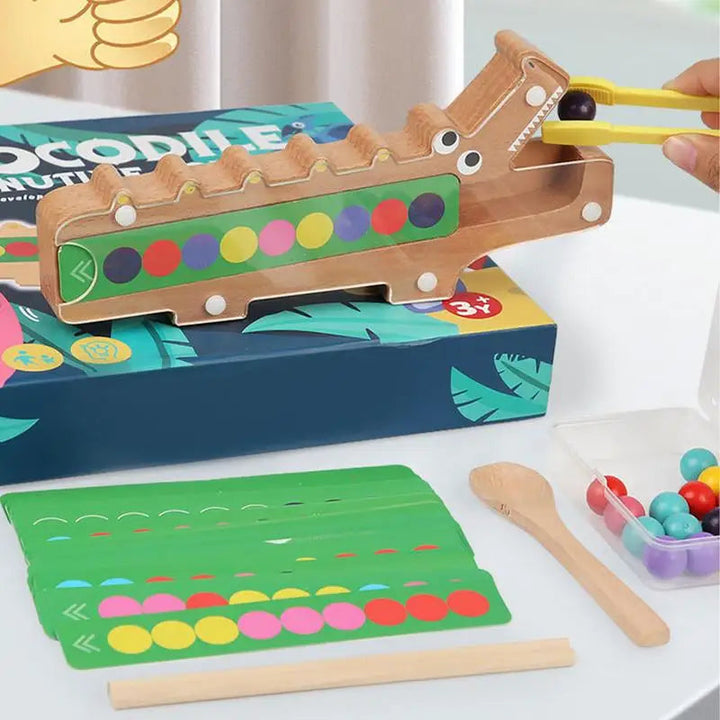 Yellow clip placing a bead into the wooden crocodile above color pattern cards and tools