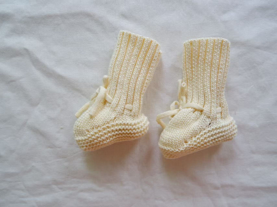 Pale yellow cotton baby booties with tall ribbed cuffs and matching ankle ties.