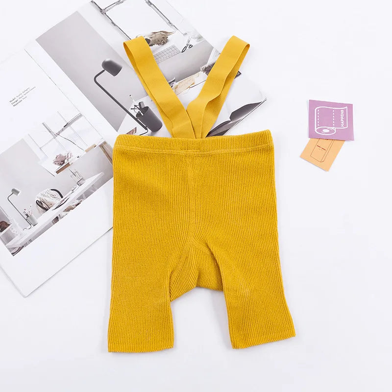 Yellow ribbed suspender shorts laid flat with matching shoulder straps.