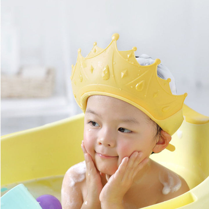 Child wearing a yellow crown-shaped bath cap in a bathtub