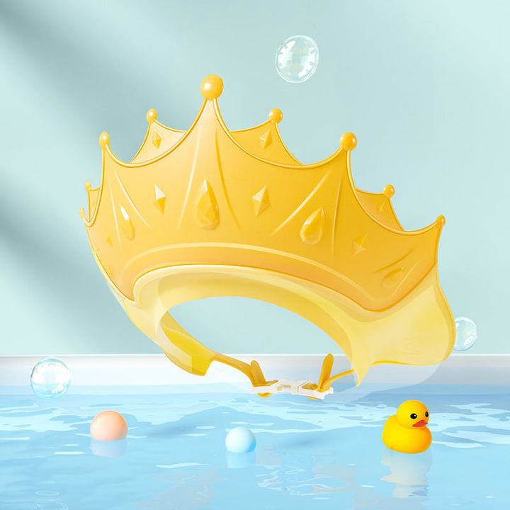 Yellow crown-shaped bath visor with an adjustable band against a bubble-themed background