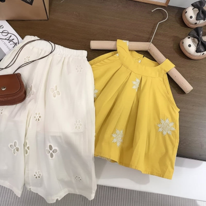 Yellow sleeveless top with white floral embroidery and white eyelet pants