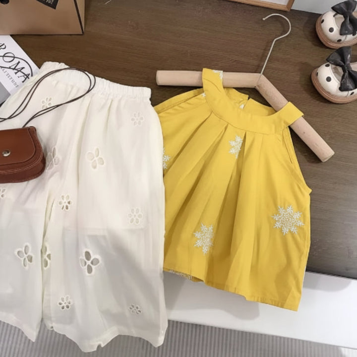 Yellow sleeveless top with white floral embroidery and white eyelet pants