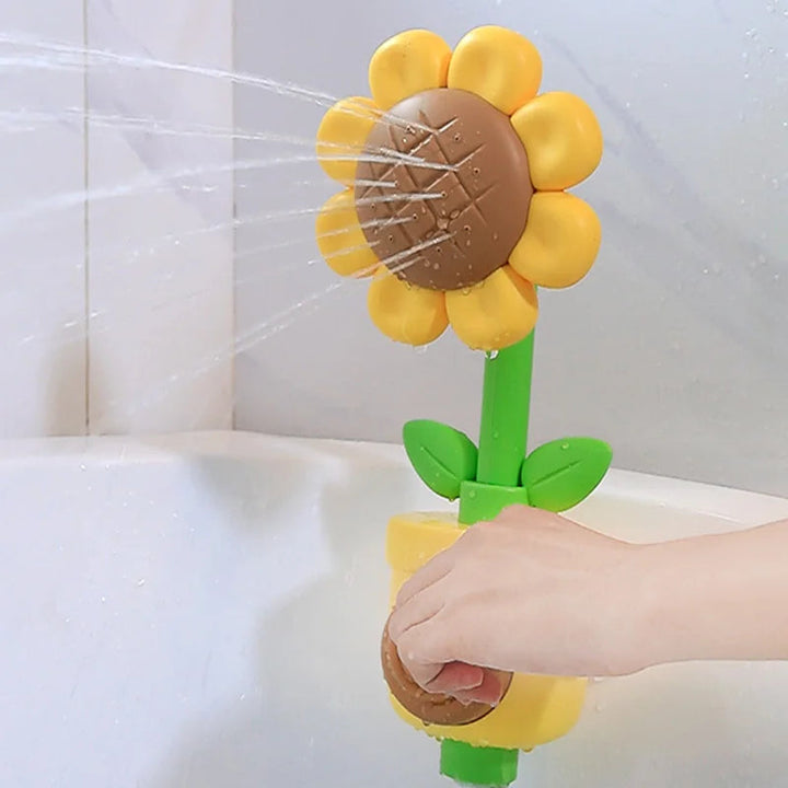 Yellow flower bath sprayer sending out streams of water while a hand presses its front button
