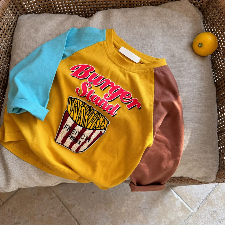 Yellow fries graphic shirt with blue and brown raglan sleeves laid on a cushioned chair