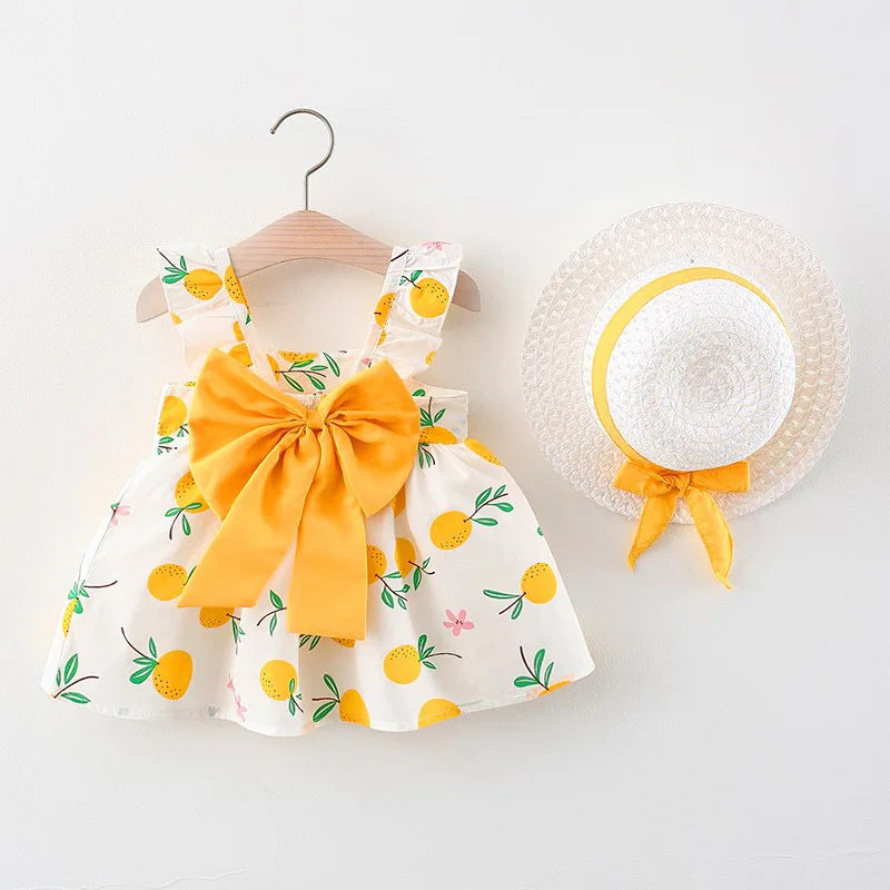 Yellow fruit-print dress with a yellow bow and straw hat with matching ribbon