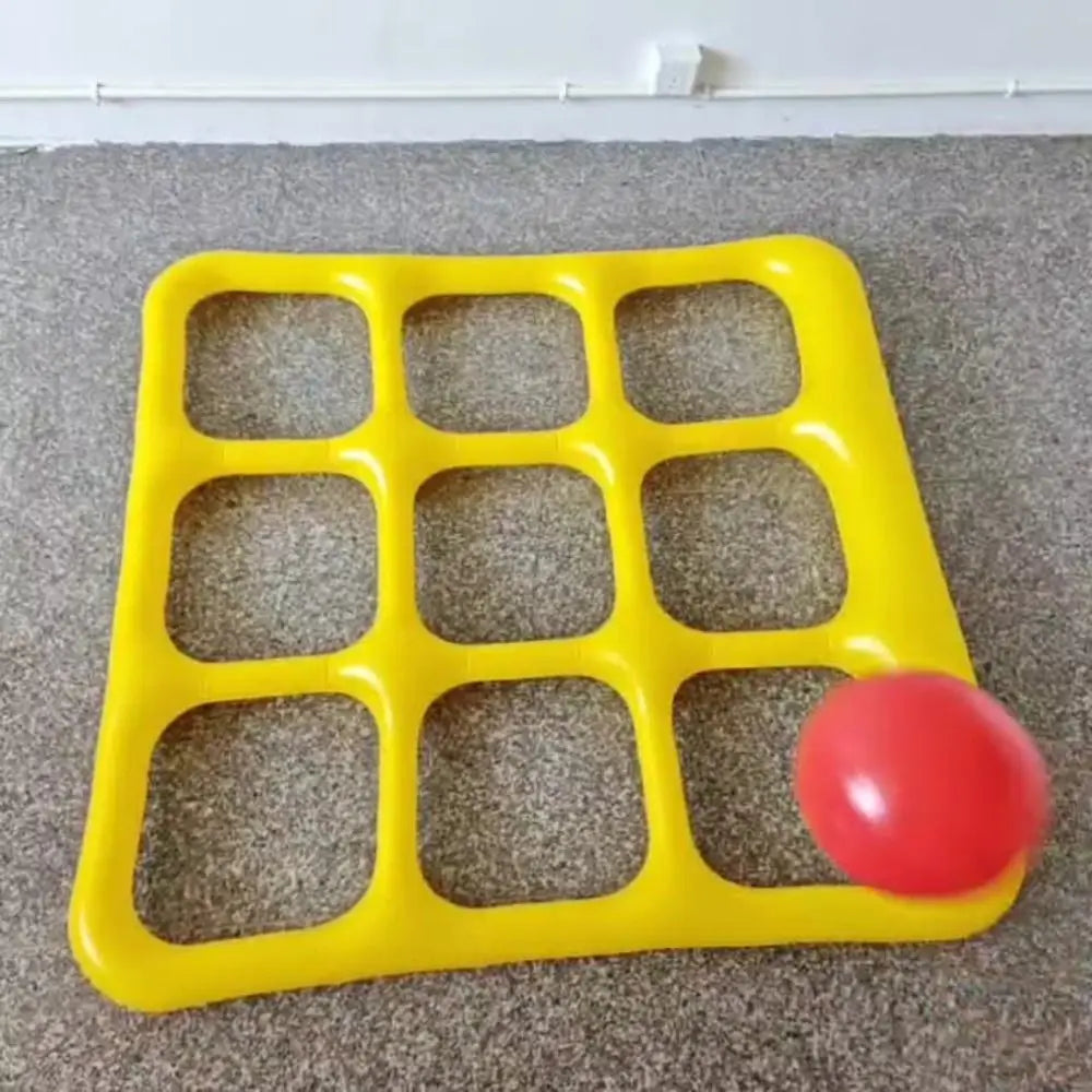 Yellow inflatable nine-space game grid with a red ball on a carpeted floor