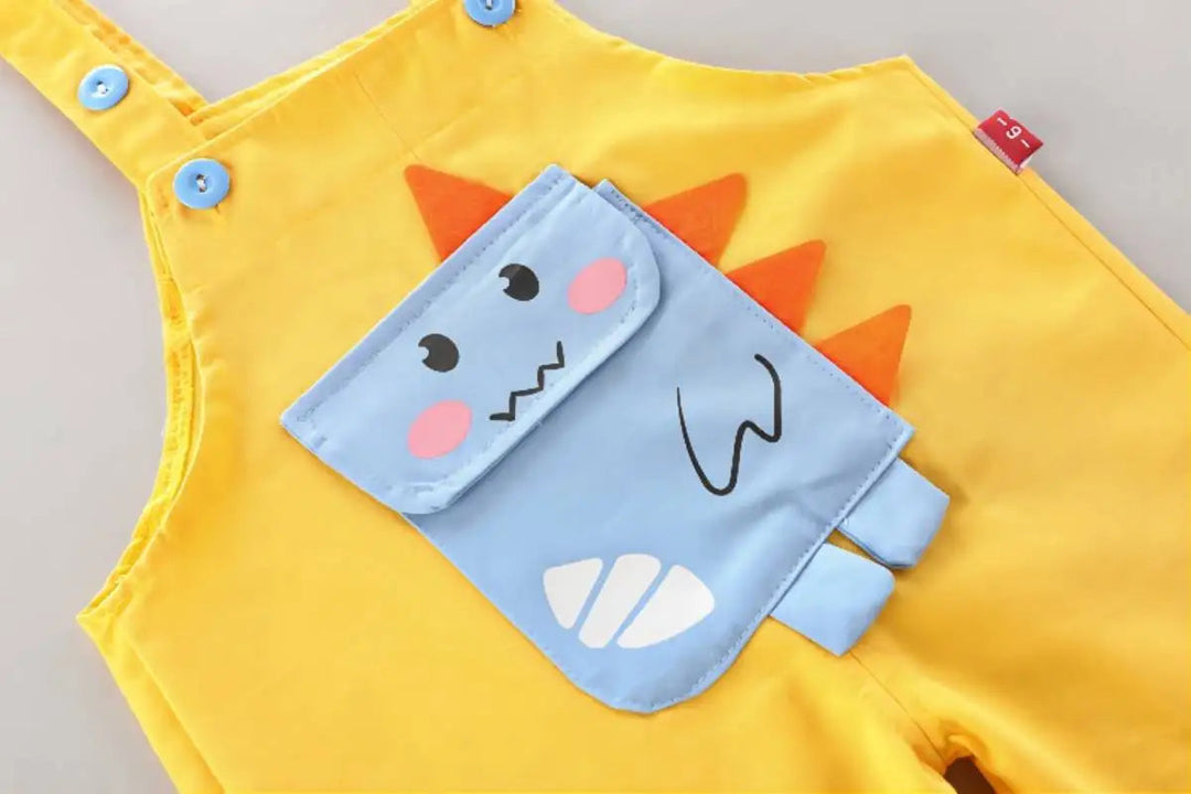 Close-up of the blue dinosaur detail and shoulder buttons on yellow overalls