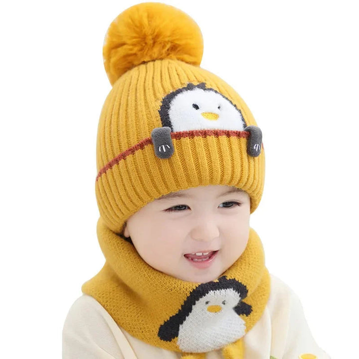 Child wearing a yellow penguin pom-pom hat and scarf on a white background