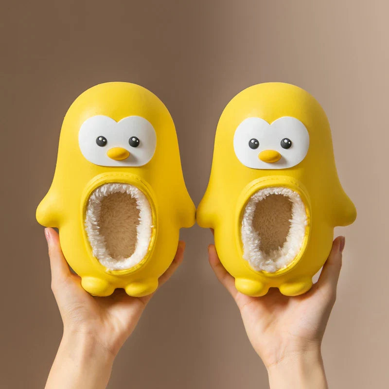 Pair of yellow penguin slippers held upright with cream-colored lining visible