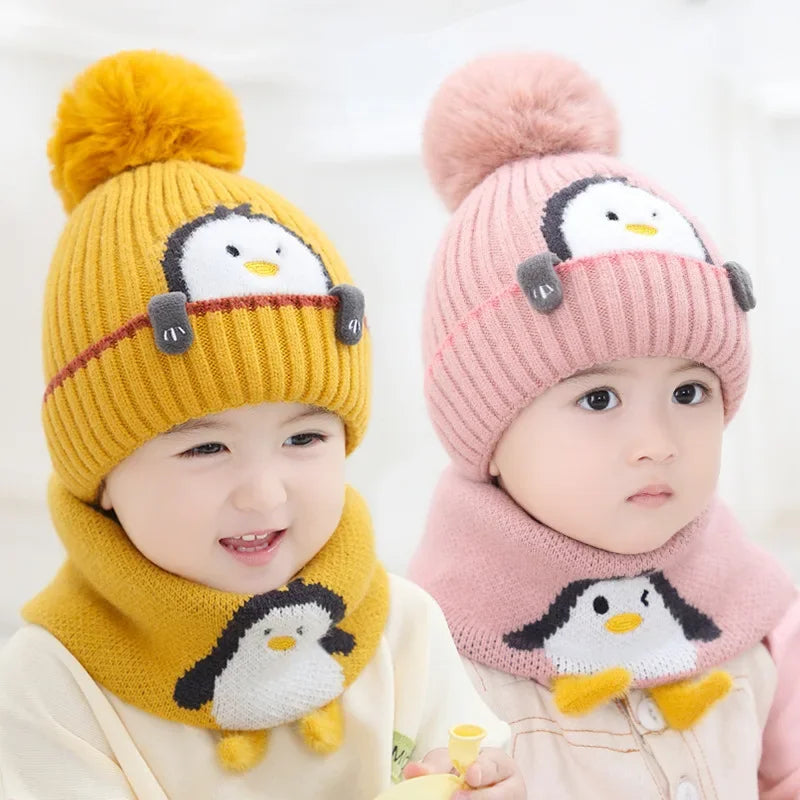 Two children wearing yellow and pink penguin hats with matching scarves