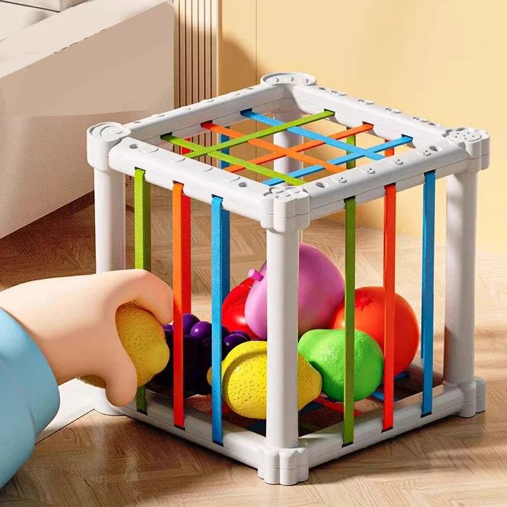 Illustrated hand moving a yellow play fruit between the cube&