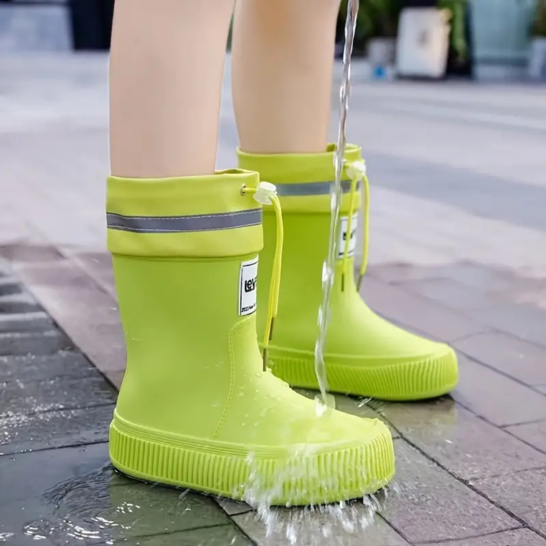 Yellow rain boots with drawstring cuffs splashed with water on paving