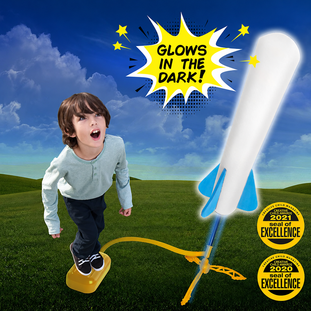 Child pressing a yellow launch pump beside a glowing white rocket with blue fins against a night-sky backdrop.