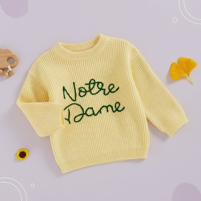 Yellow sweater with green script embroidery and one sleeve folded across the front.
