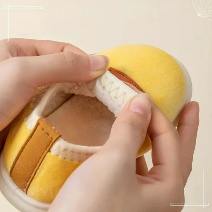 Hands stretching the stitched opening of a yellow slip-on winter slipper