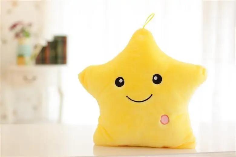 Yellow star-shaped plush pillow with a smiling face and pink button