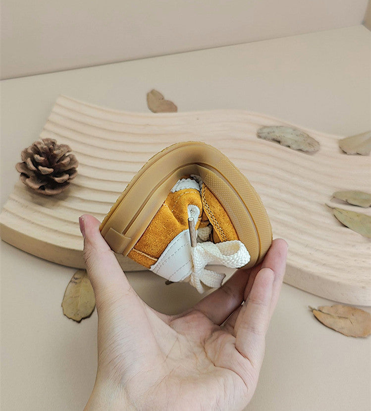 A yellow sneaker folded in one hand to show the flexibility of its rubber sole