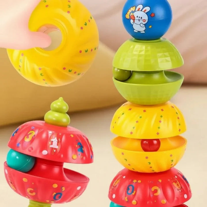Hand holding a yellow stacking piece beside a tower of red, yellow, and green pieces