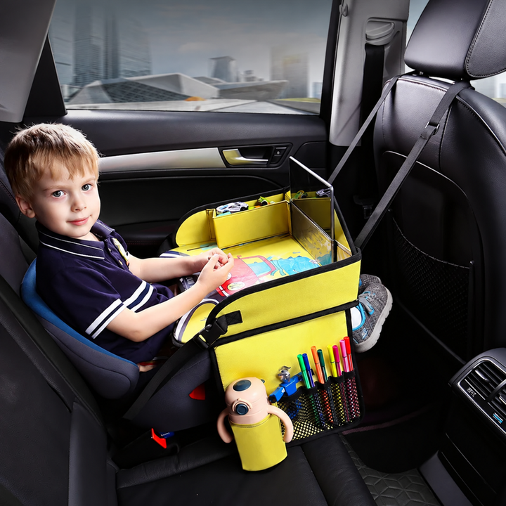 Child using a yellow travel tray in a car seat, with markers and a bottle in the side pockets