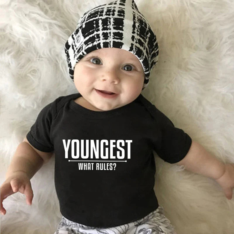 Baby wearing a black Youngest top with the slogan What rules?